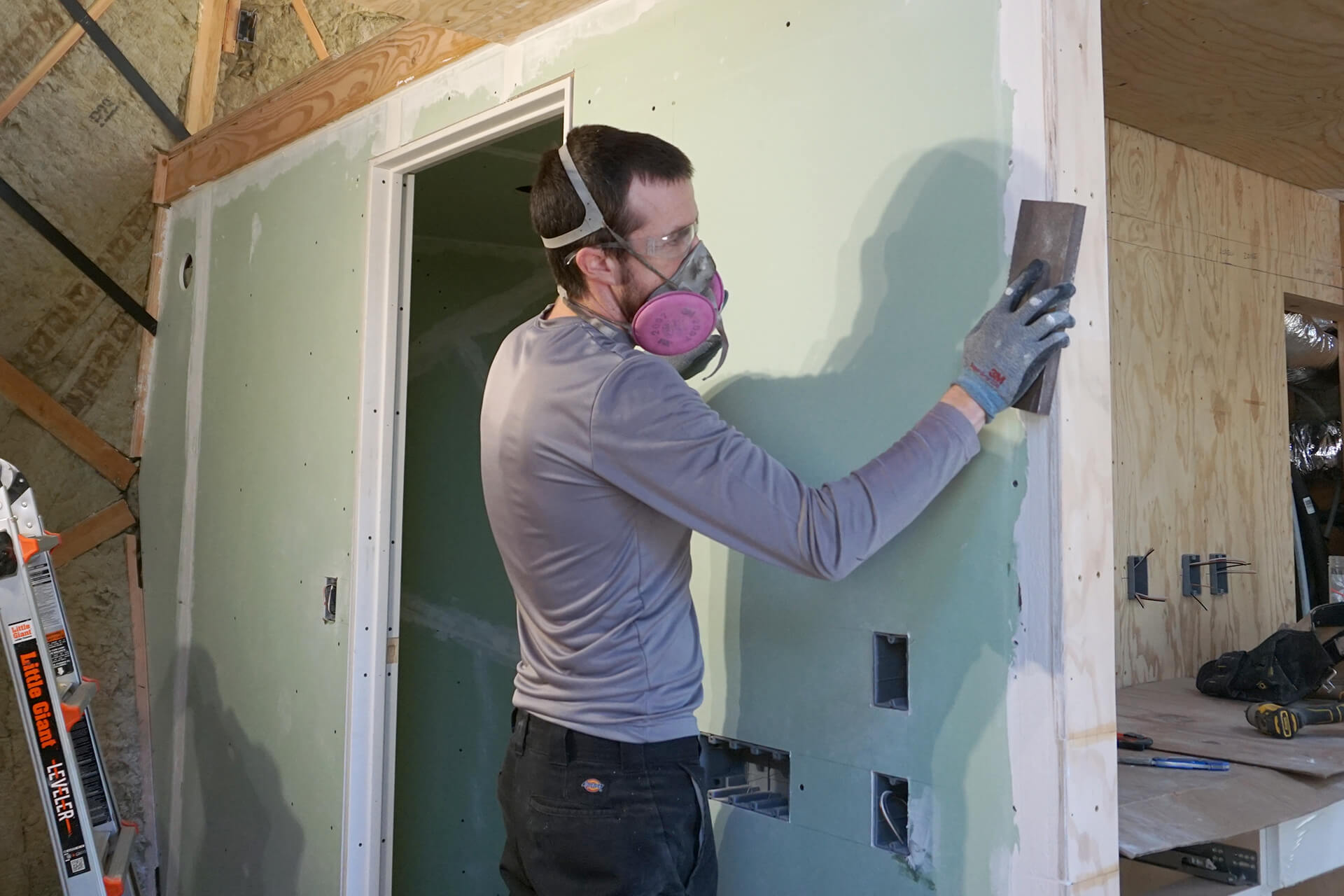 Sanding drywall mud to a smooth finish.